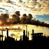 smoke stacks against cloudy sunny sky